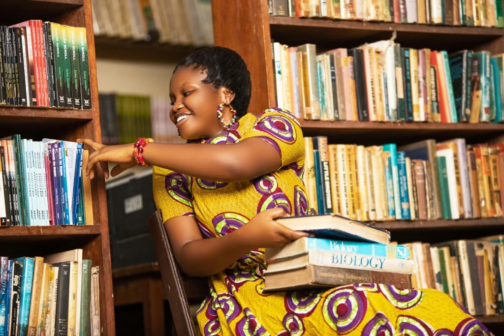 Smiling African woman reading books in a Ghana library, showcasing vibrant culture and education.