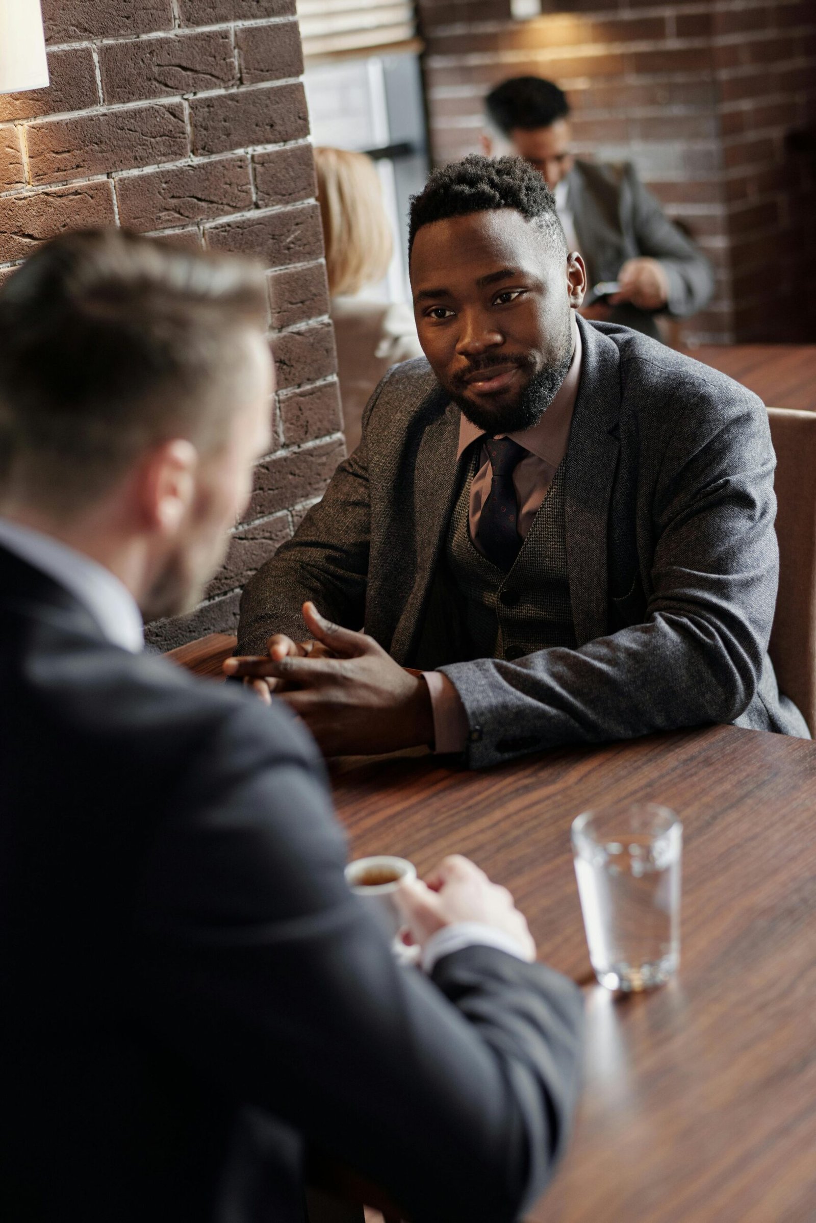 Two businessmen in suits chatting during a coffee break in a stylish café.