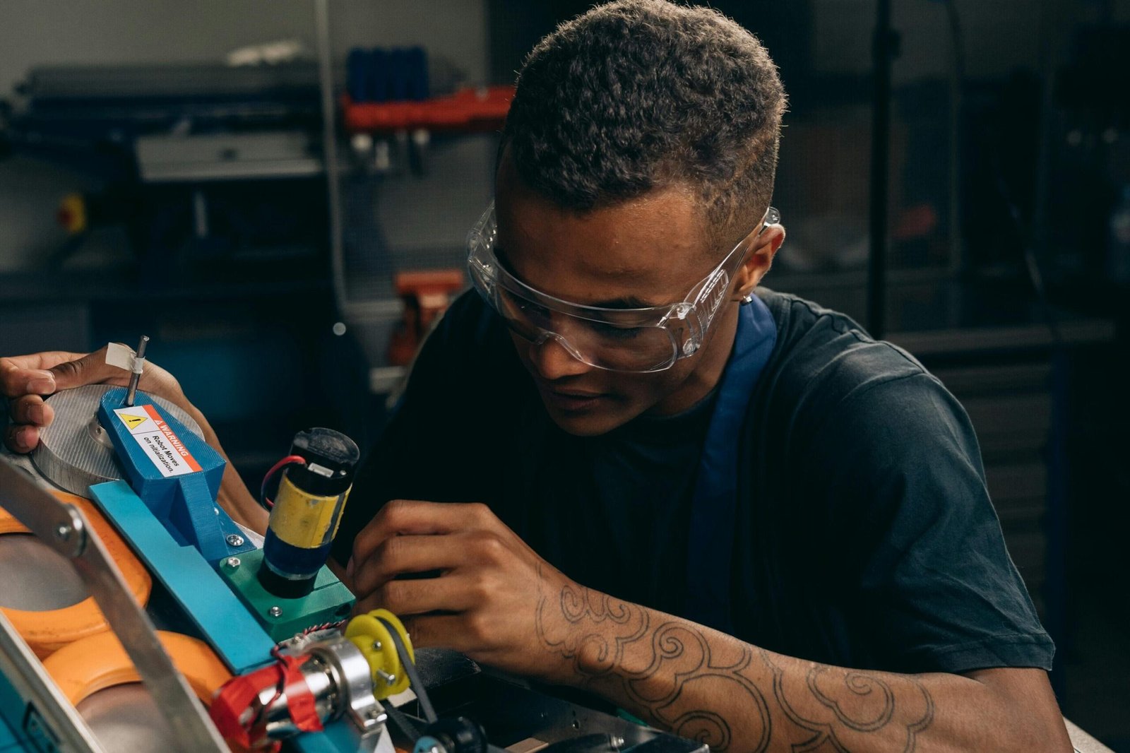 Focused young engineer wearing safety glasses adjusting machinery with precision in an industrial setting.