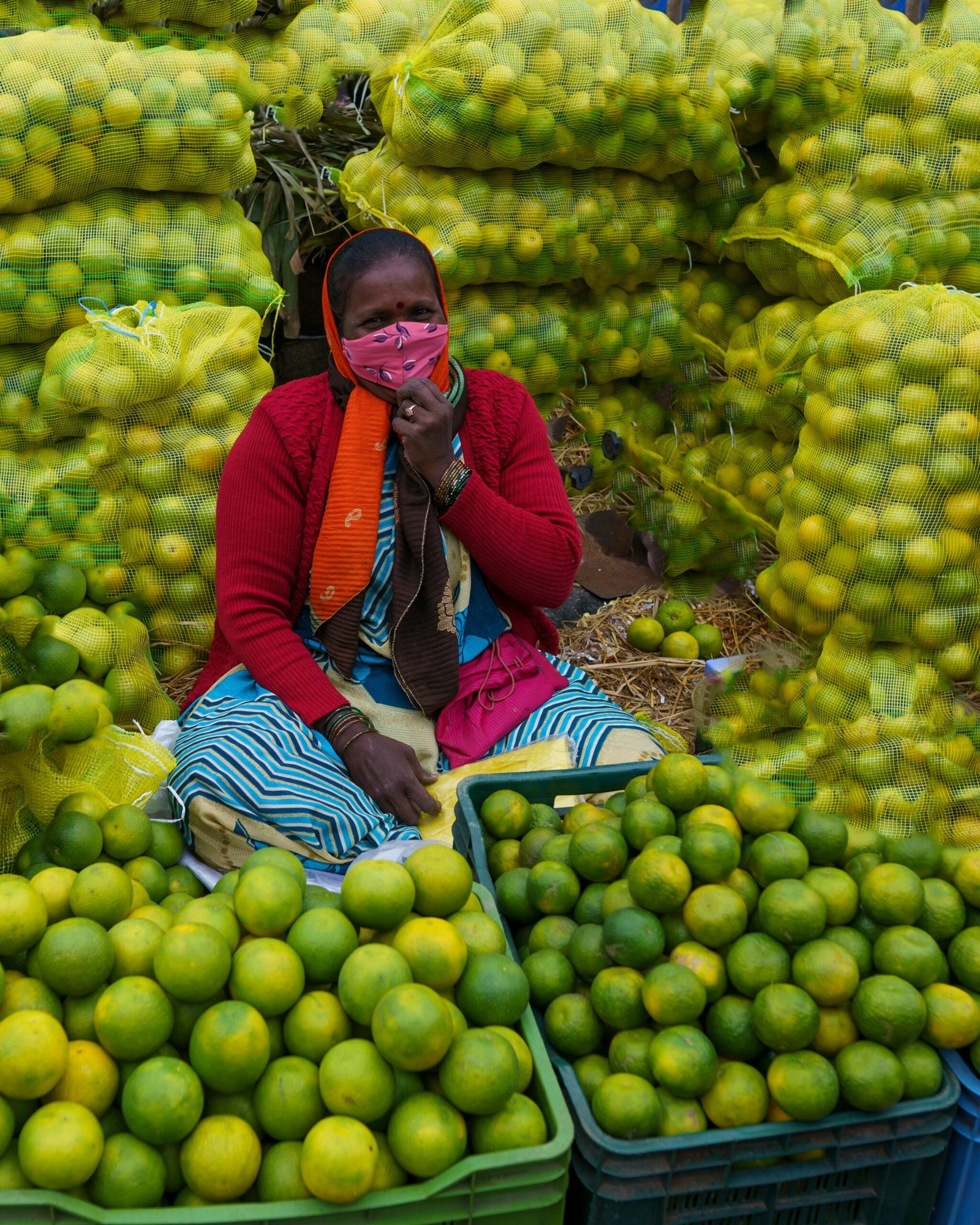 Colorful display of fresh limes at a bustling Bengaluru market with a local vendor.